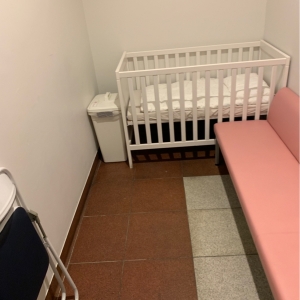 ベビーベッドには布団が敷いてあり、オムツ用のゴミ箱とゆったり座れる長いソファー・パイプ椅子もあり。